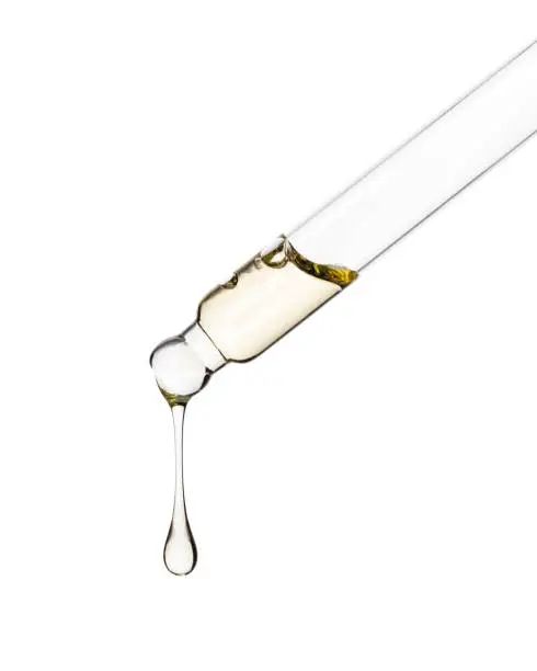 Photo of Cosmetic dropper with yellow oil. Glass dropper isolated on a white background. Path saved.