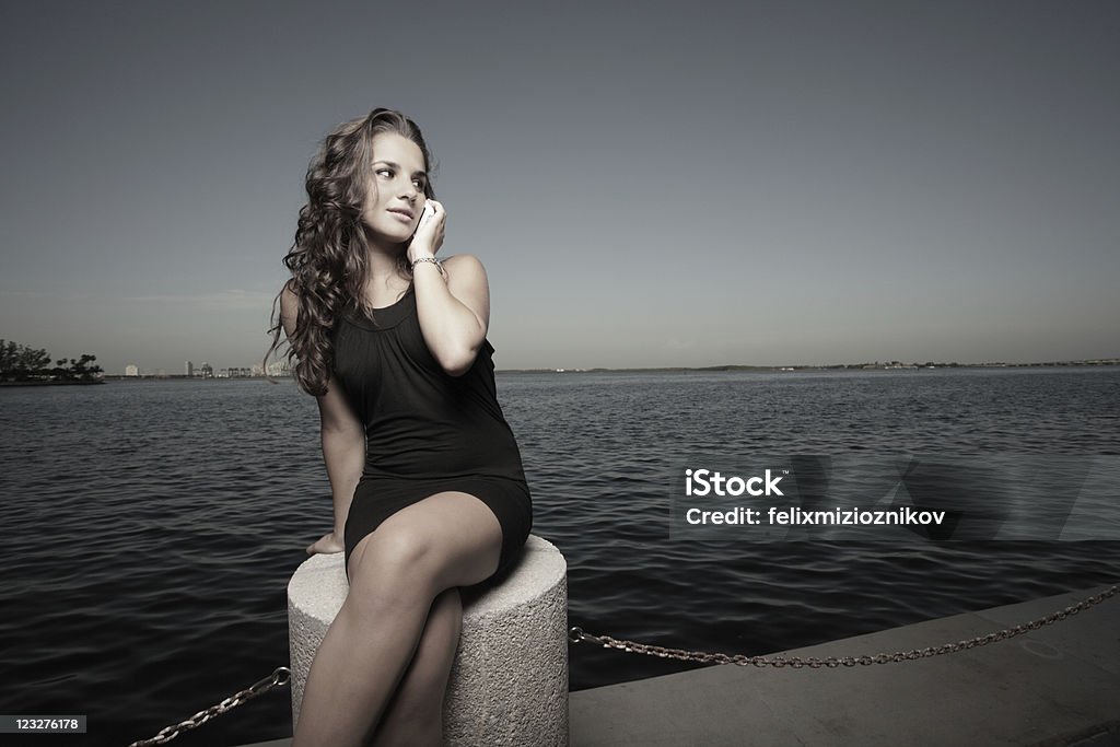 Atractiva mujer sentada junto a la bahía - Foto de stock de 20 a 29 años libre de derechos
