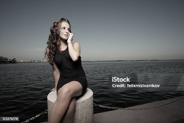 Atractiva Mujer Sentada Junto A La Bahía Foto de stock y más banco de imágenes de 20 a 29 años - 20 a 29 años, Adulto, Adulto joven