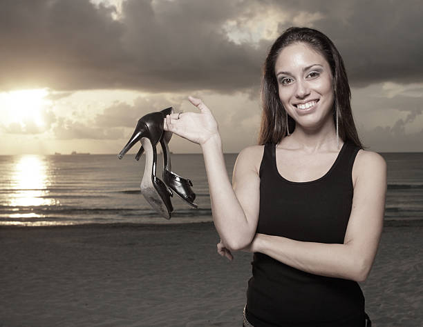 mulher segurando seu salto alto na praia - high heels flash - fotografias e filmes do acervo