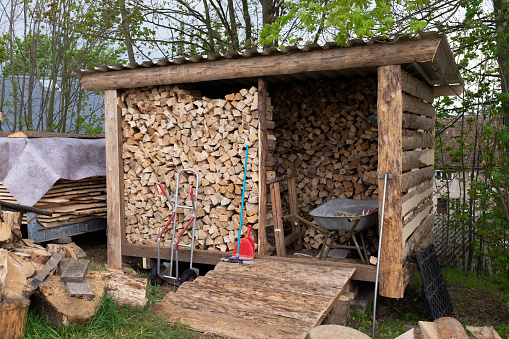 Firewood for the winter piled up in a DIY storage shed in the garden