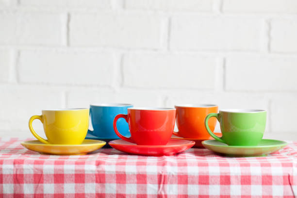 Colorful cups on the white background of a brick wall. Background with copy space. Selective focus.