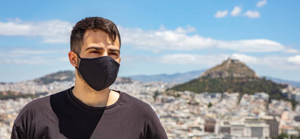 atenas acrópole, grécia dias de coronavírus. jovem usando máscara facial protetora na paisagem da cidade e fundo azul do céu. - antiquities acropolis athens greece greece - fotografias e filmes do acervo