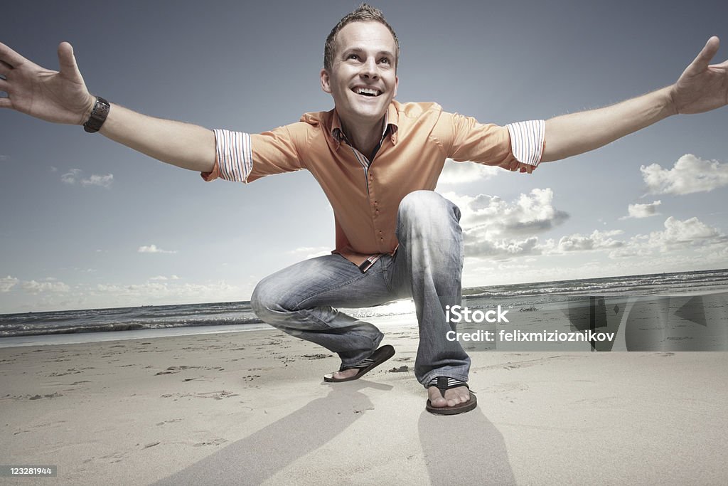 Man squatting on the sand Young man squatting on the sand with the sunrise or sunset in the background 30-39 Years Stock Photo