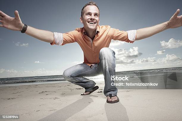 Man Squatting On The Sand Stock Photo - Download Image Now - 30-39 Years, Adult, Adults Only