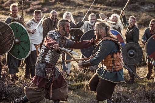 A hoard of Weapon wielding viking warriors fighting in a battlefield scene in the moors