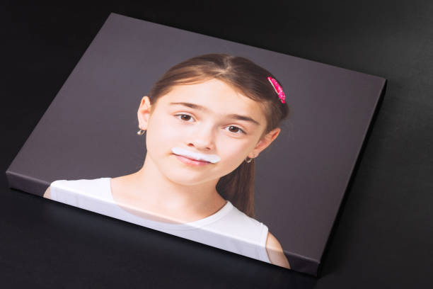 Canvas print of young girl with milk mustache Canvas print of a young girl with milk mustache isolated on a black background. Holiday or special occasion gift concept. artists canvas photos stock pictures, royalty-free photos & images