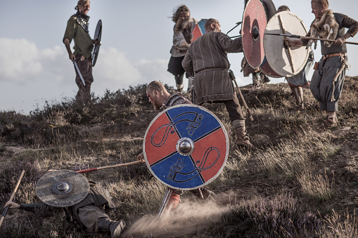 A hoard of Weapon wielding viking warriors fighting in a battlefield scene in the moors