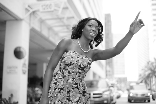 Young black woman hailing a cab in a city setting 