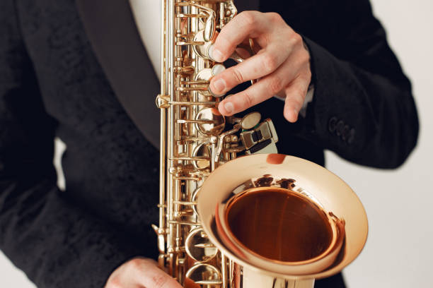 Man in black suit standing with a saxophone stock photo