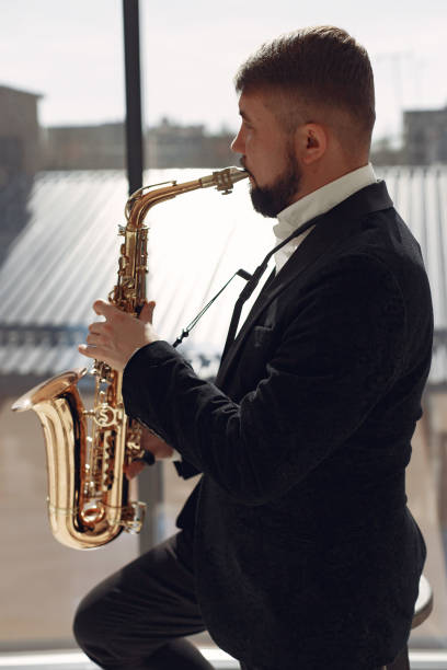 istock Man in black suit standing with a saxophone 1232863029