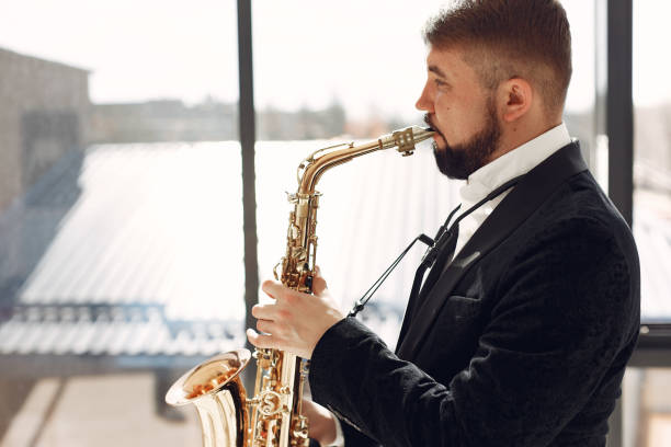 istock Man in black suit standing with a saxophone 1232864554