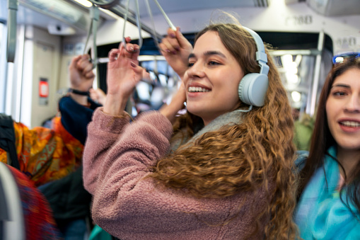 Beautiful young woman, listening music with headphone at the public transport