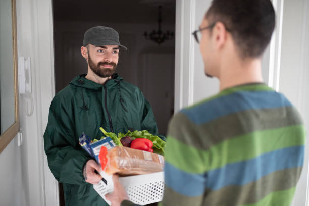 istock Courier delivering green groceries in a crate to customer 1232890330