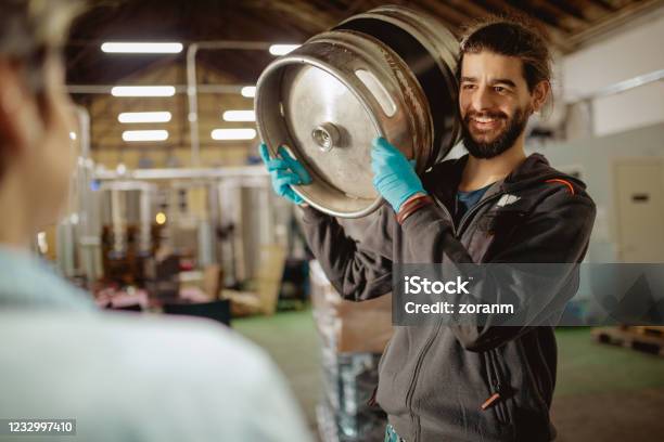 Worker Carrying Beer Barrel On Shoulder And Smiling At Manager Stock Photo - Download Image Now