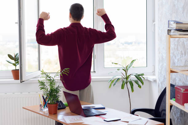 istock Office worker does gymnastics standing by the window 1233255853
