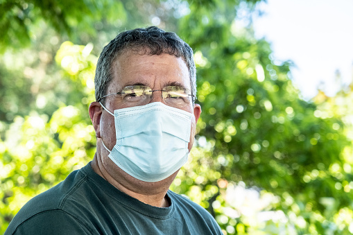 Overweight hispanic senior man wearing a protective mask due Covid-19 state of emergency