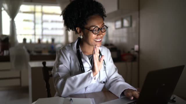 Dokter wanita melakukan panggilan video di laptop di rumah
