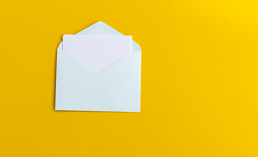 white sheet of paper folds and gets into envelope on yellow background, communication concept.