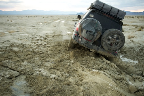 4x4 or truck stuck in the mud at sunset on the Applegate Trail, Black Rock Desert, NW Nevada, US.  Illustrates the concepts of 