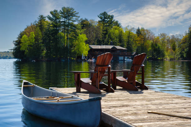 canot attaché à un quai avec des chaises de muskoka - maison de campagne photos et images de collection