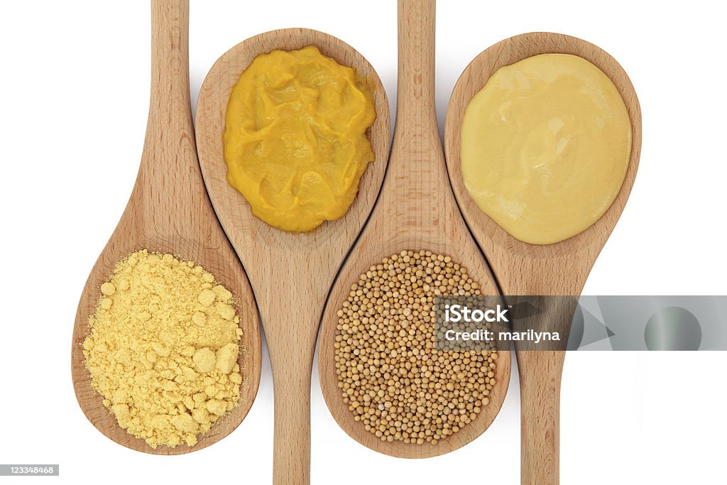 Mustard Selection Mustard selection of powder, hot english, seed and dijon in wooden spoons isolated over white background. Choice Stock Photo