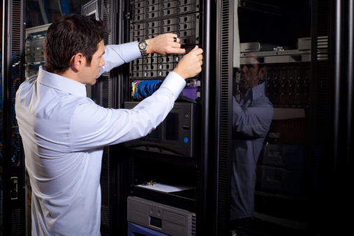 An IT technician is shown repairing data drives on a server network