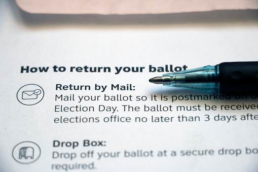 Closeup of vote-by-mail return ballot instructions on an official election mail envelope with pen lying on top.