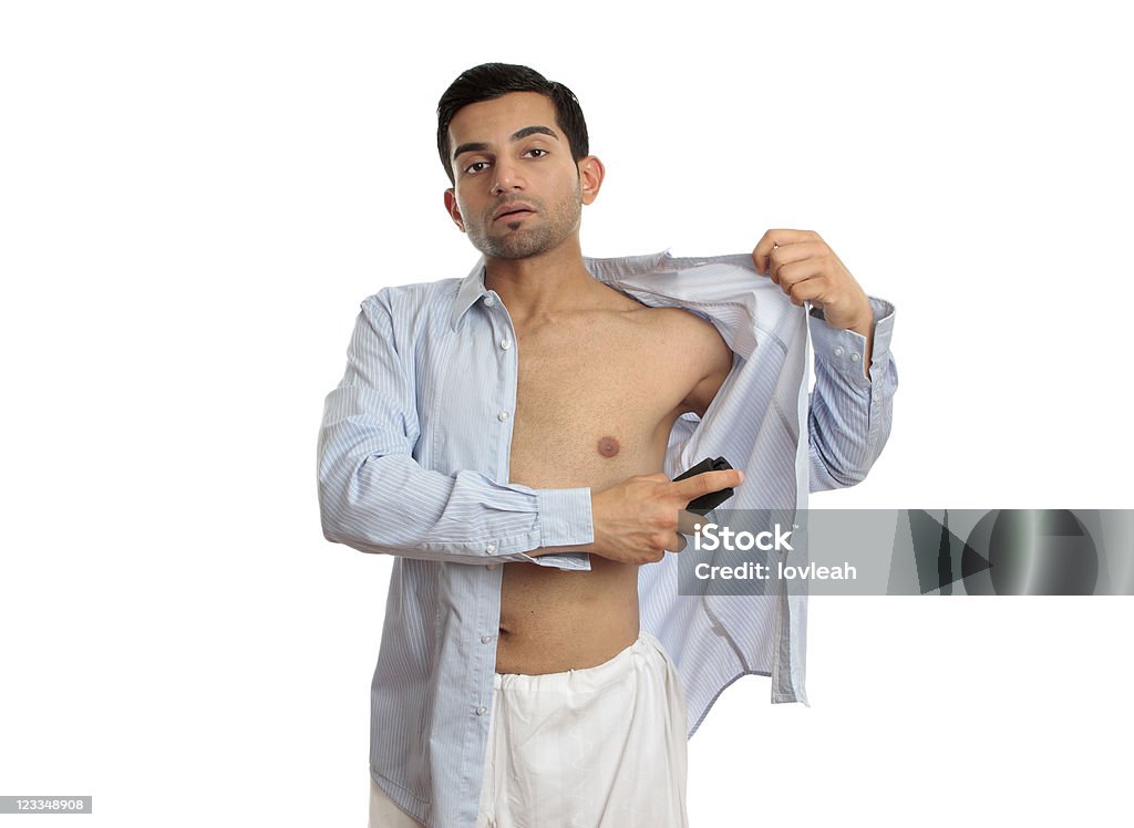 Man spraying deodorant A man spraying a deodorant body spray under arms while getting dressed. Button Down Shirt Stock Photo