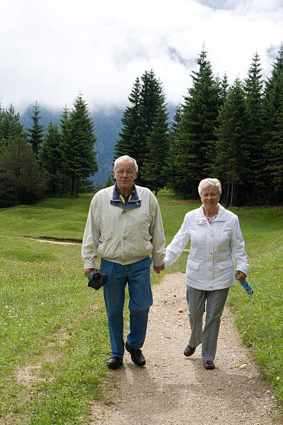 Photo of an elderly couple during their hike with backpacks, reached the top of the mountain