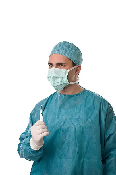 portrait of a surgeon with surgical mask, gown and scalpel, isolated on white