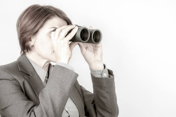 Business woman in suit looking through binoculars