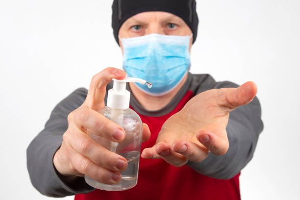 istock man in a protective medical mask during quarantine disinfects his hands from the virus using a special alcohol gel 1233668606
