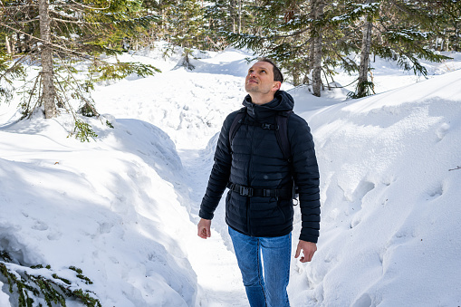 Young happy man on mountain trail with snow in Okuhida villages Shinhotaka Ropeway in Gifu Prefecture, Japan park looking up wearing coat and jeans