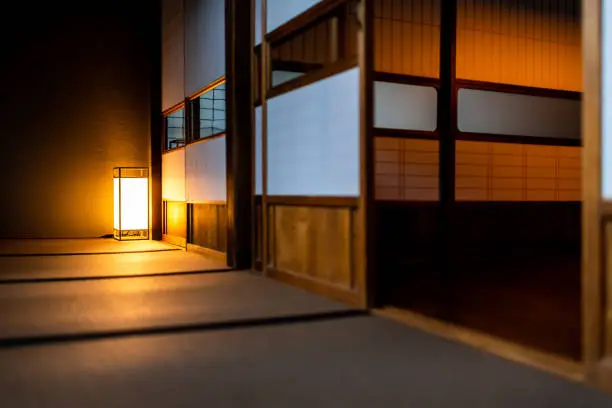 Photo of Traditional japanese room low angle view in house or ryokan with open shoji sliding paper doors tatami mat floor and lamp illuminated at night with nobody