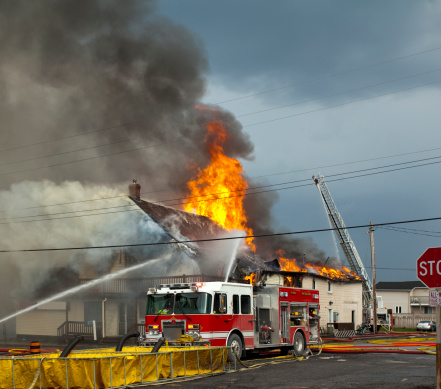 fire fighters responding to fire in a large building engulfed in flames