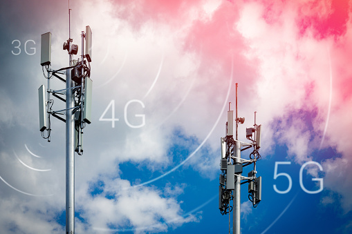 Two telecommunication towers with 4G, 5G transmitters. Cellular base stations with transmitting antennas on a telecommunication tower on a background of blue sky with pink-yellow clouds. Tinted