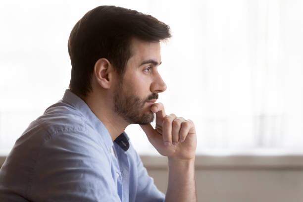 istock Distracted from job study young man touching chin, looking away. 1233750973