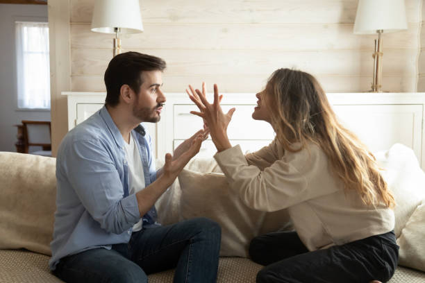 Emotional annoyed stressed couple arguing at home. Emotional annoyed stressed couple sitting on couch, arguing at home. Angry irritated nervous woman man shouting at each other, figuring out relations, feeling outraged, relationship problems concept. couple stock pictures, royalty-free photos & images