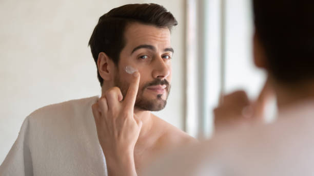 tysiąclecia przystojny człowiek stosowania nawilżające po krem do golenia. - men shaving human face bathroom zdjęcia i obrazy z banku zdjęć