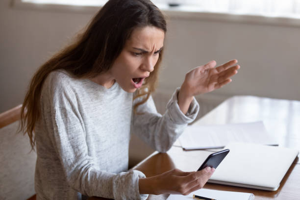 istock Outraged young mixed race girl looking at mobile phone screen. 1233752033