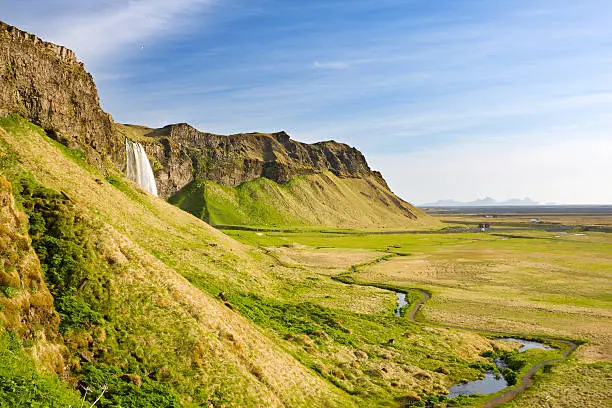 View alongside a cliff in the southwest of Iceland to the famous Seljalandsfoss.