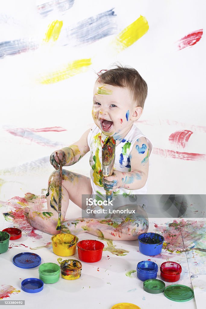 Young child covered in colorful paint and making mess little girl bedaubed with bright colors Activity Stock Photo