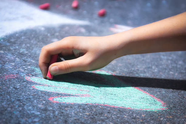 Children Hand Drawing Picture with Sidewalk Chalk stock photo