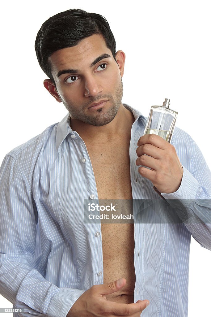 Man with cologne while dressing A man holding a bottle of cologne while getting dressed Adult Stock Photo