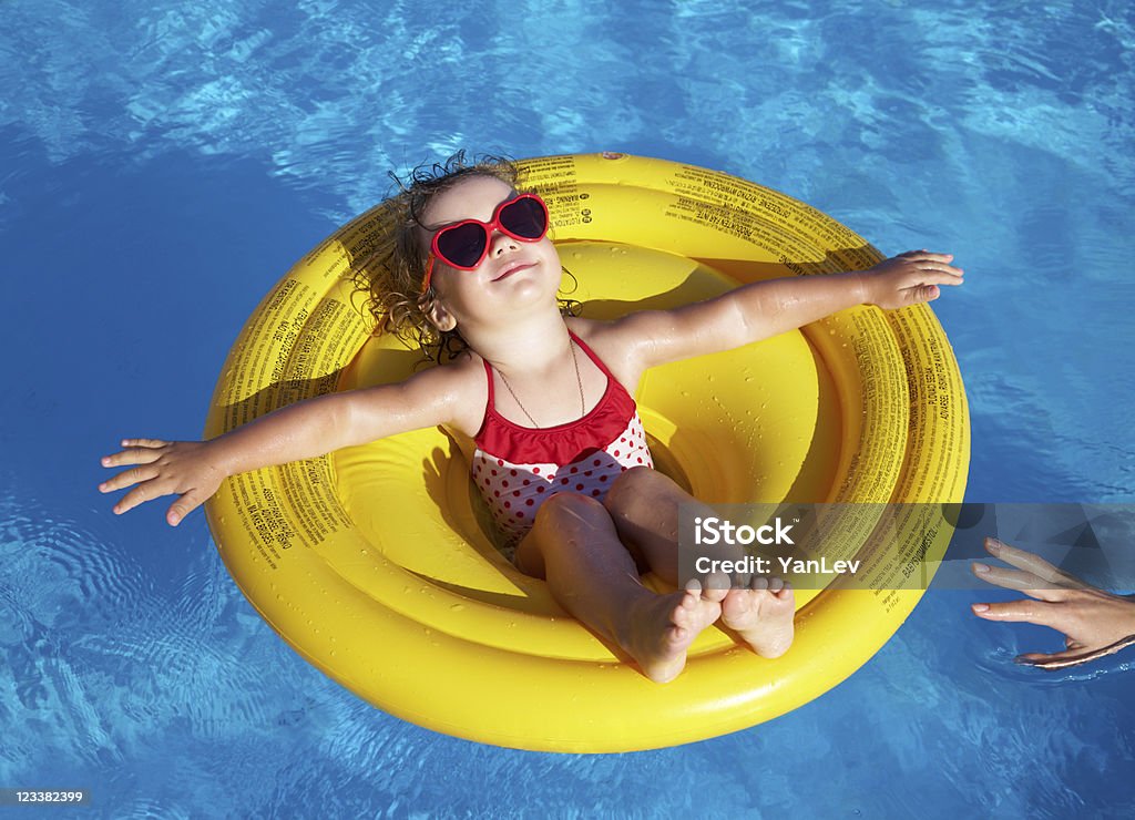 Little girl swims in  pool Funny little girl swims in a pool in an yellow life preserver Swimming Pool Stock Photo