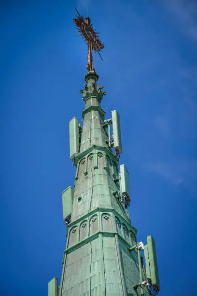 Photo of 5g 4g cell phone antennas on the oxidized copper gable of a cathedral