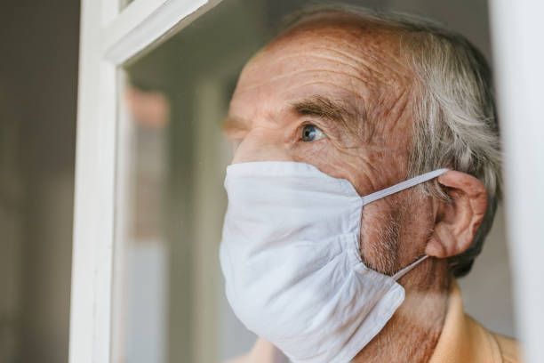 istock Elderly man wearing mask looking through the window 1233857324