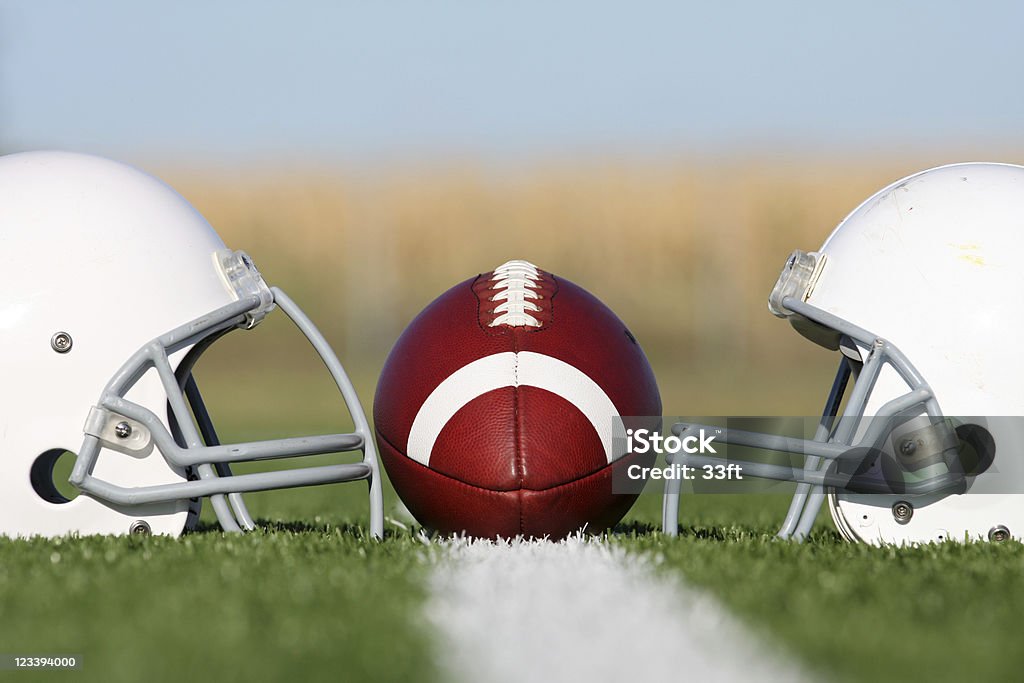 Fútbol americano y casco en campo - Foto de stock de Casco de fútbol americano libre de derechos