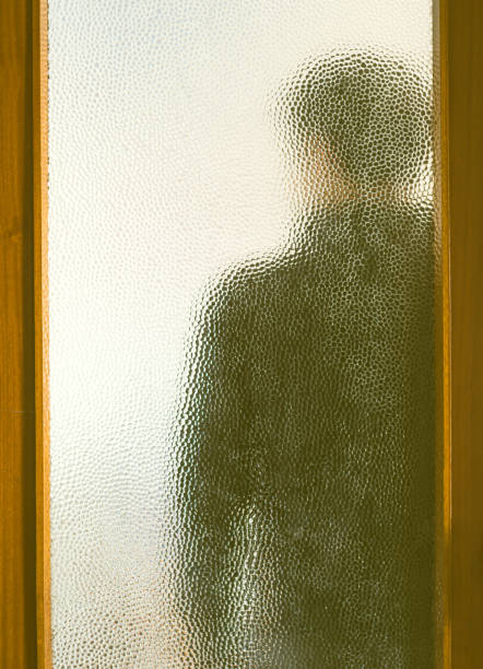 istock Man in black behind closed door through glass 1234360544